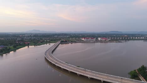 aerial view of a curved bridge over a river, with cityscape in the background