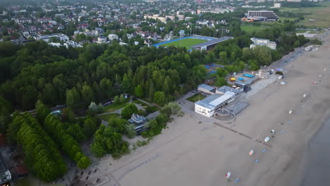 Aerial view tilting over the beach, revealing Parnu city, summer dusk in Estonia