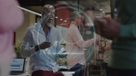 animation of cyber security text, magnifying glass icon over african american man laughing at office