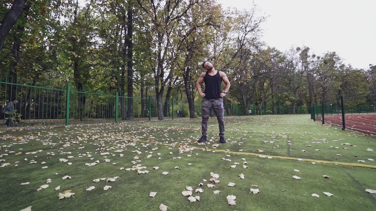Muscular sportsman doing exercises in the open air. Strong athlete training his body on the stadium on nature background. Slow motion.