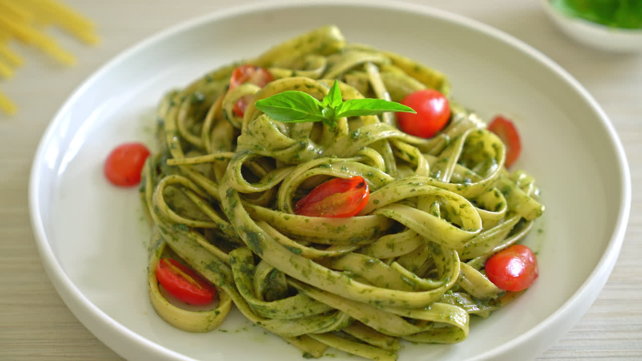 espaguetis fettuccine con salsa pesto y tomates - estilo de comida vegana y vegetariana
