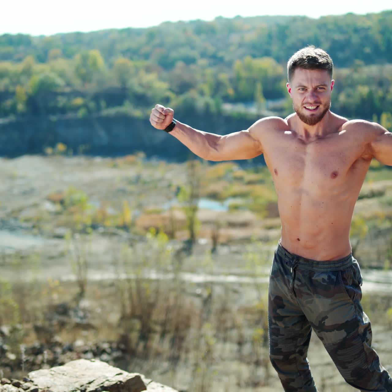 Portrait of bodybuilder on nature background in summer. Handsome sportsman posing on camera and showing his muscular body outdoors.