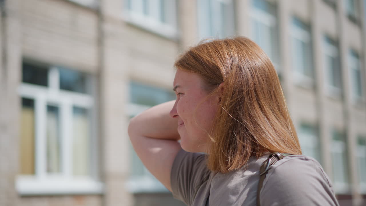 Signora tesa in piedi all'aperto alla luce del sole, si tocca i lati della testa mentre si guarda intorno con espressione ansiosa, l'emozione di preoccupazione e incertezza traspare dal suo viso