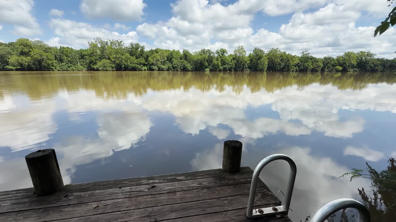 Static shot of Virginia River in the U.S., showing a wooden dock in the foreground and cloud reflections in the calm water