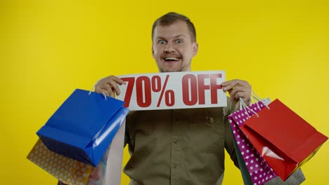 Happy-man-dancing,-celebrating,-showing-shopping-bags-and-Up-To-70-percent-Off-inscription