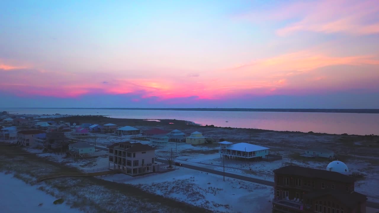 석양에 아름다운 해변 마을 위로 뒤로 날아가는 드론