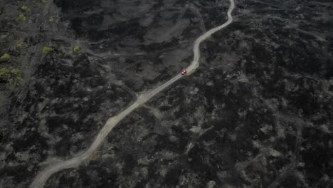 red jeep drives on new road built on volcanic lava at mount batur bali