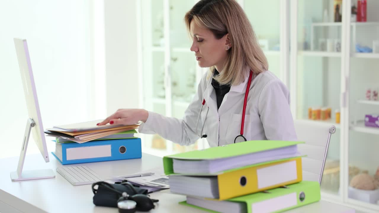 Doctor working at her desk with computer and files