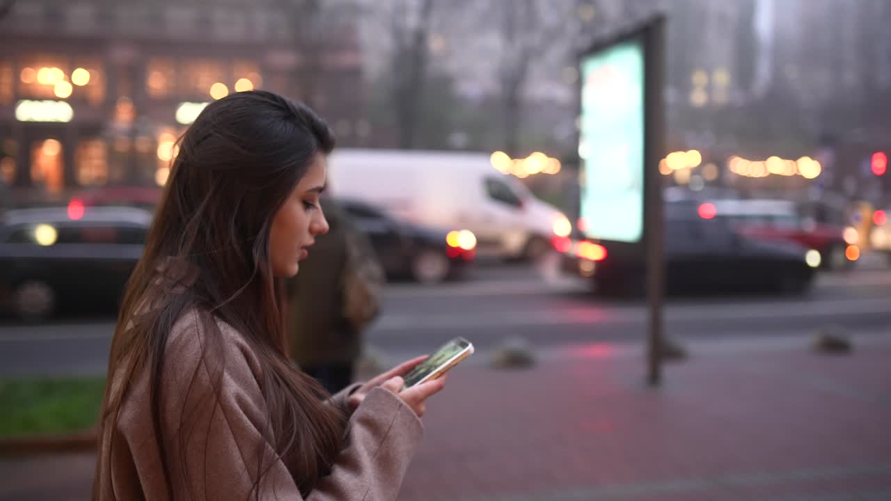 mujer usando un teléfono inteligente en la calle de la ciudad por la noche