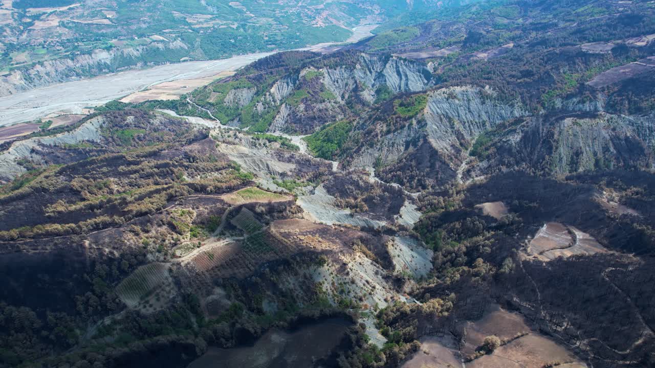 Mountain ranges with black pine forests burned by summer wildfires, extreme heat and global warming effects