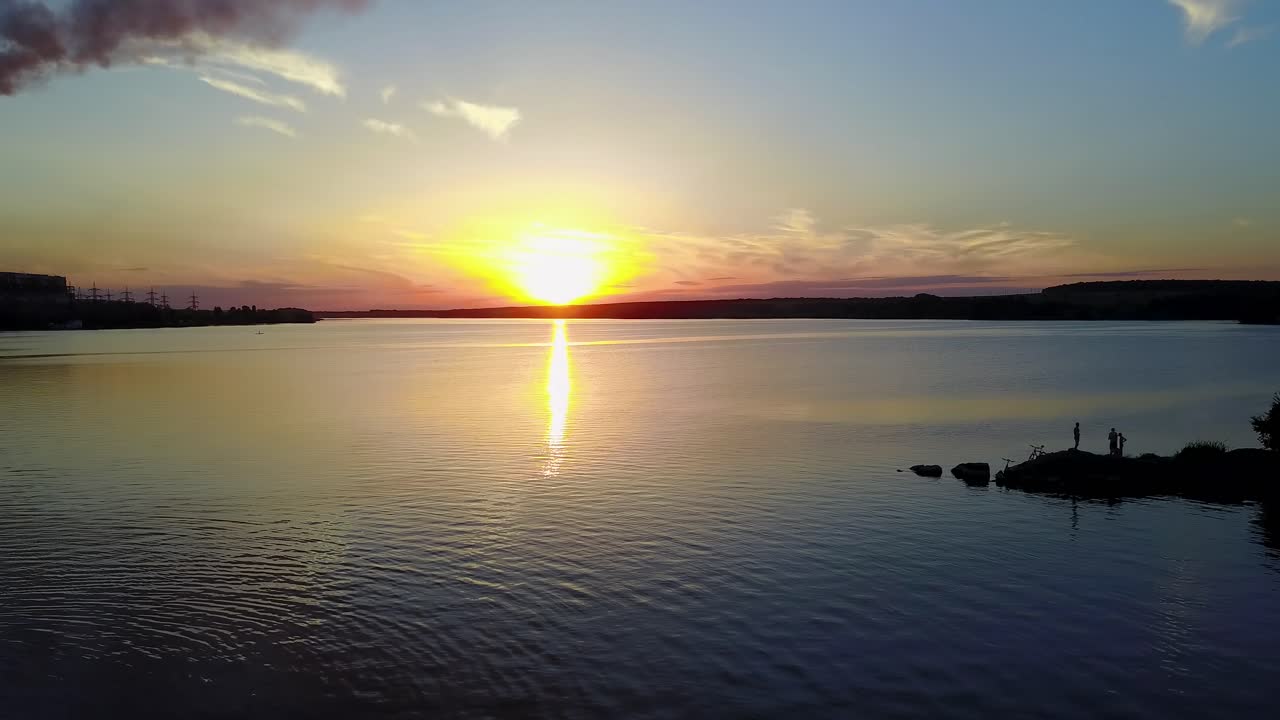 Industrial evening landscape with factory pipes and river at sunset
