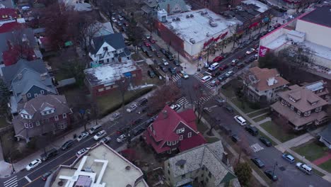 Drone-pan-up-in-central-Brooklyn,-New-York,-just-before-sunset,-going-from-rooftops-to-revealing-the-Manhattan-skyline-in-the-distance