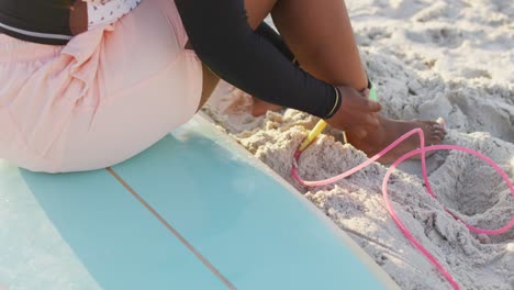 african american woman preparing before surfing on sunny beach