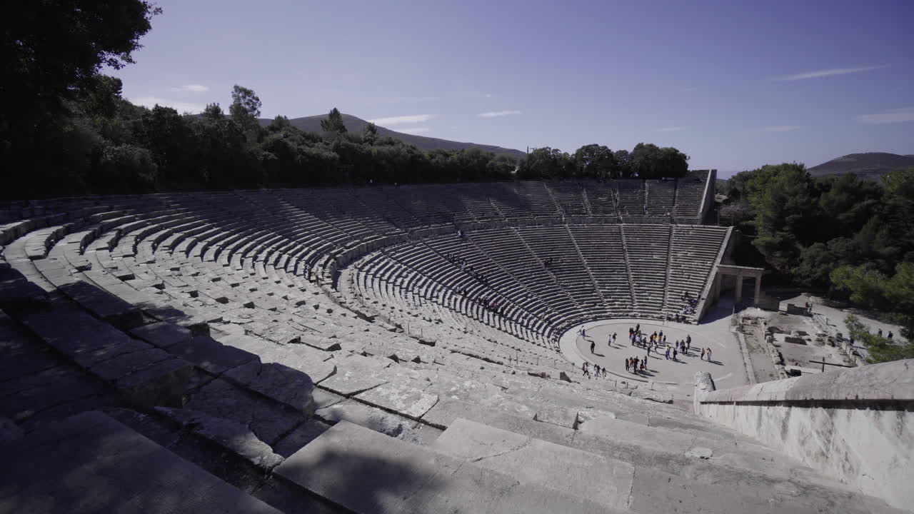 People Visit The Famous Theatre Of Ancient Greece On A Sunny Day - aerial panning shot