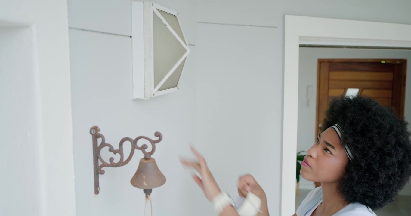 African American woman grabbing tape, tapping box sconce prepping paint at front entry, copy space