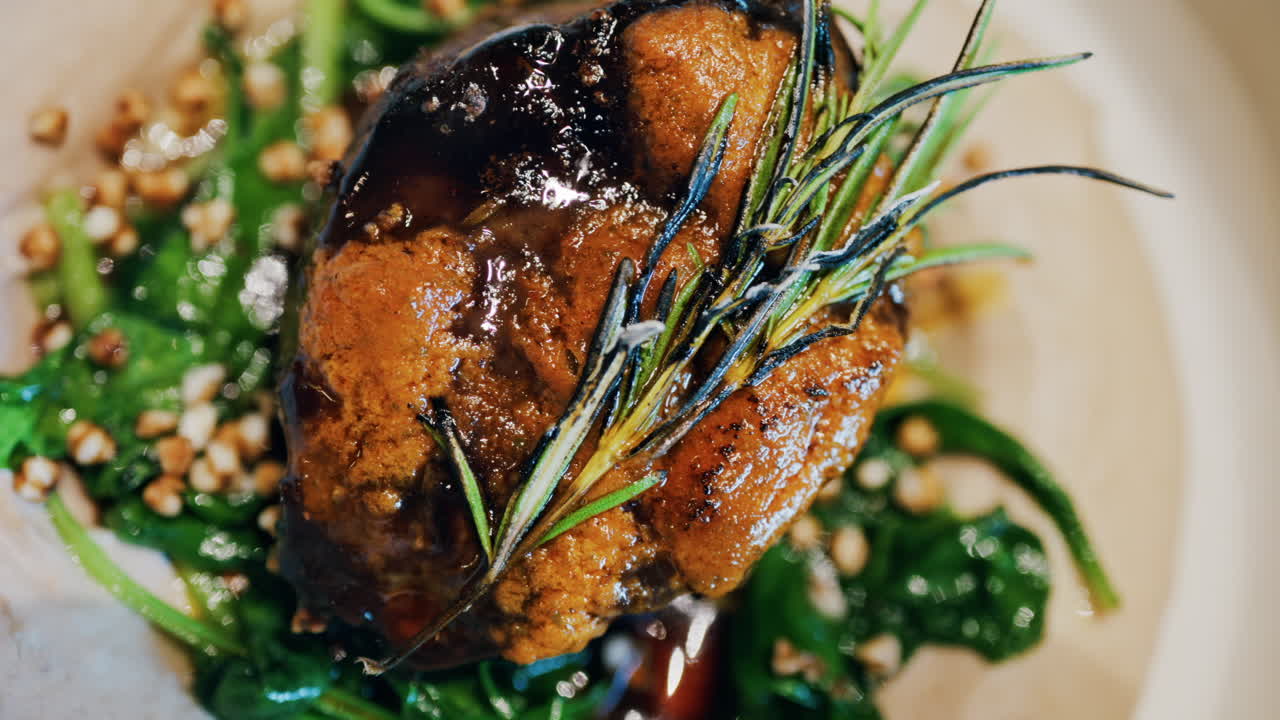 Close up of a beautifully plated beef filet, topped with a golden crust and garnished with rosemary