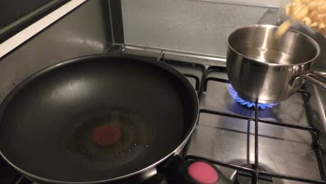 pasta wird in einen mit wasser gefüllten topf gegossen, der auf dem herd steht