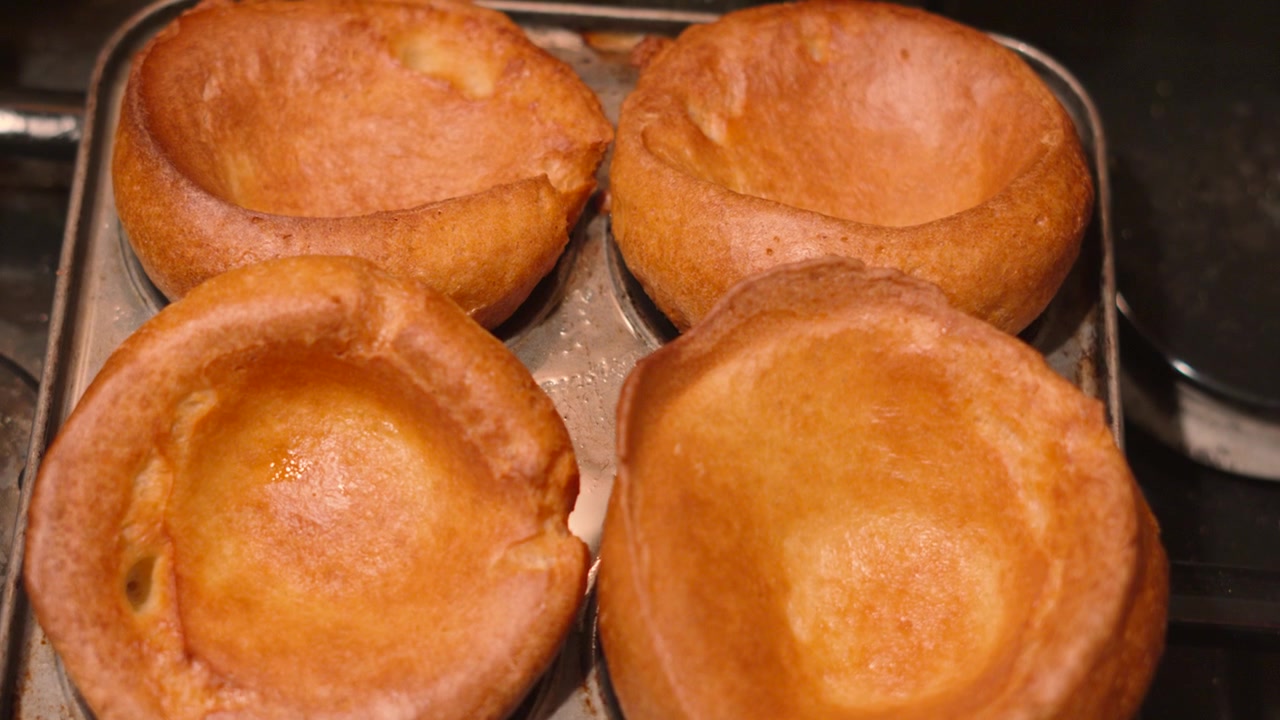 Deliziosi e dorati tradizionali Yorkshire Pudding britannici in teglia dopo la cottura in forno, pronti per essere serviti al ristorante o a casa per la cena della domenica. 4K.