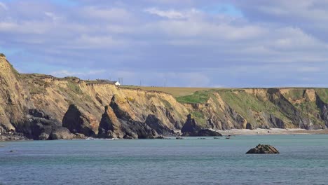 ireland epic locations people walking on distant beach and dramatic sea stacks and calm seas copper coast waterford in spring