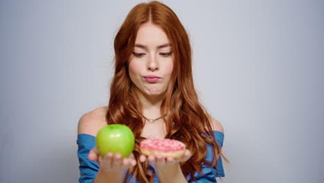 chica dudosa tomando decisiones en el estudio. mujer sonriente eligiendo manzana en el interior