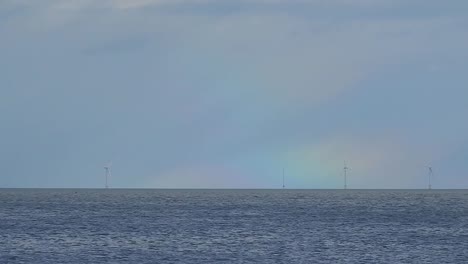 regenbogen neben der meereslandschaft eines offshore-windkraftparks mit erneuerbarer energie