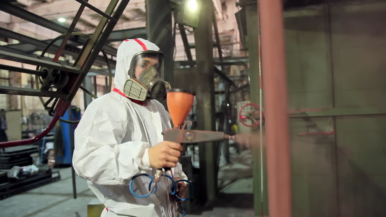 Man holding powder coating sprayer. Worker painting metal products with a spray gun