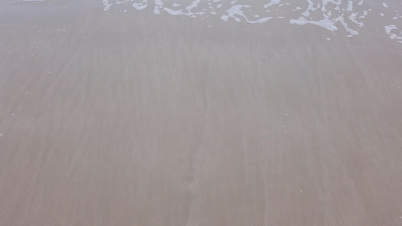 agua de ola de mar natural en cámara lenta con espuma en la playa blanca de belleza arenosa, paisaje marino de playa de verano