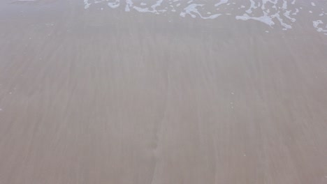 agua de ola de mar natural en cámara lenta con espuma en la playa blanca de belleza arenosa, paisaje marino de playa de verano