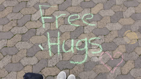 young woman drawing using chalk writing free hugs happy teenage girl on playground concept