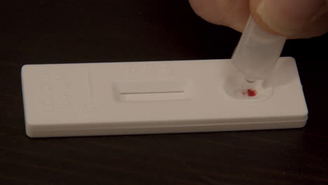buffer fluid being added to drop of blood on covid-19 antibodies test - close