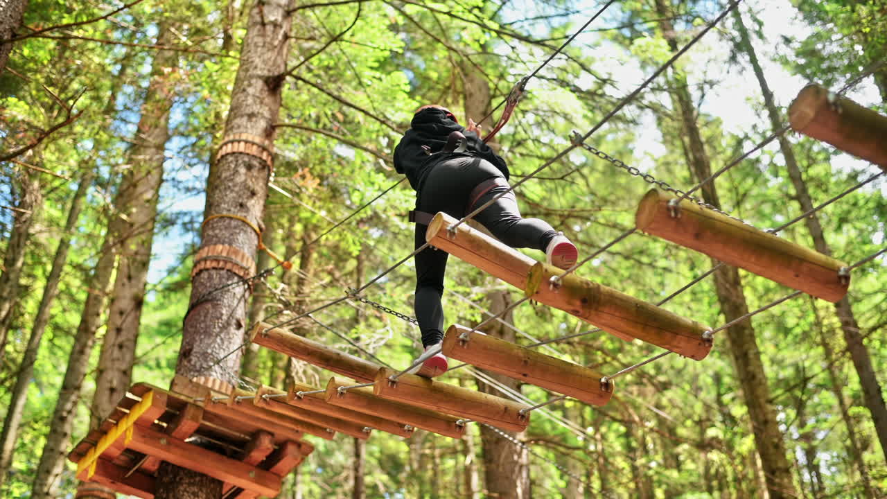 View of a woman at climbing adventure park in the Carpathians, greenery around, Romania