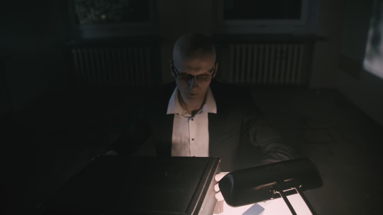Pale bald accountant looks opens the briefcase in the weird room at night