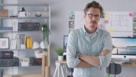 portrait of male architect in office with folded arms standing by desk