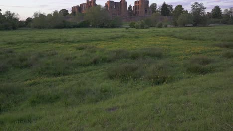 Late-evening-shot-of-the-ruins-of-Kenilworth-castle-across-the-meadow-in-the-summer-,-a-typical-scene-of-the-English-countryside