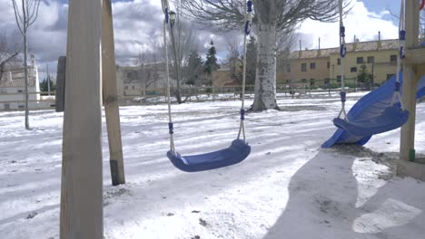 Empty-swing-set-in-a-childrends-park-covered-in-snow