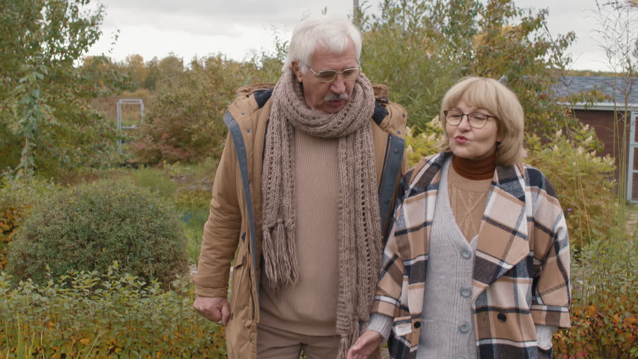An elderly couple walking in a garden in autumn