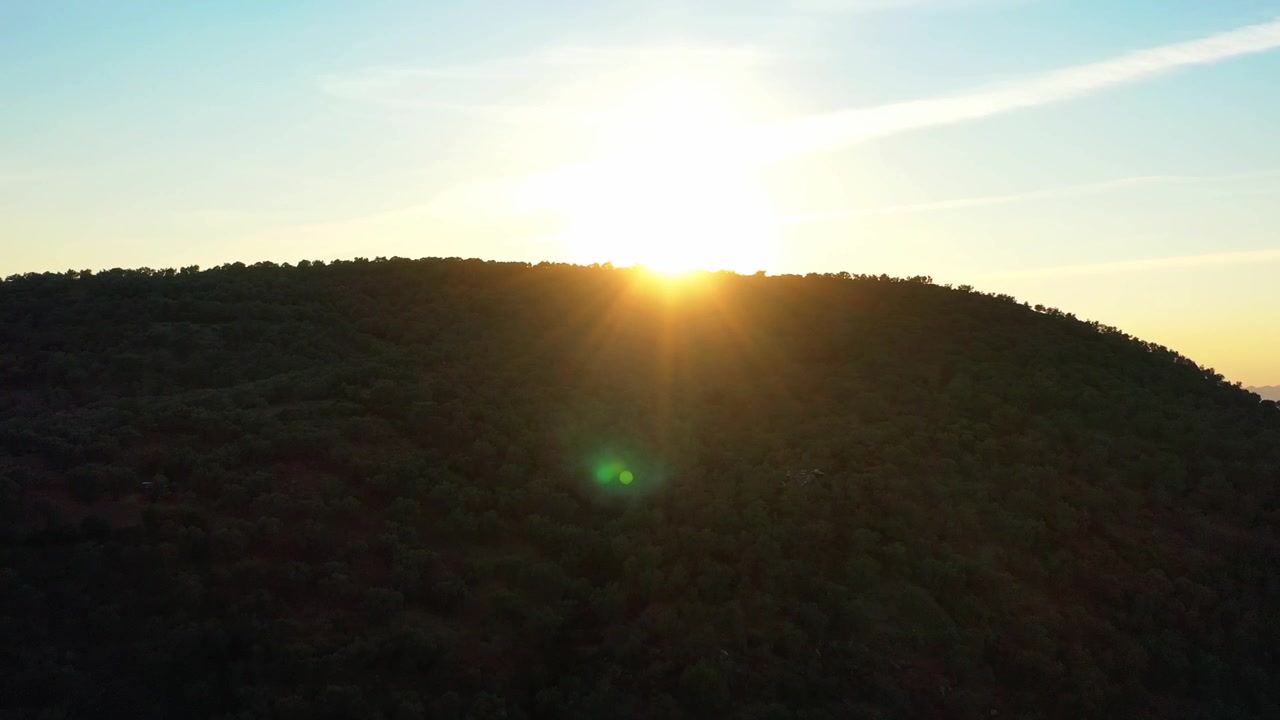 Golden sunrise over a mountain ridge in the Moroccan landscape with dramatic sunlight and natural silhouettes under a clear sky. Cinematic nature scenery ideal for travel and documentary projects.