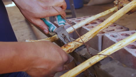 a close up of a man's hands as he uses pliers to tighten some wire around a wooden stick