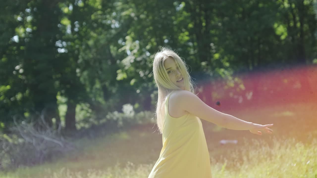 노란색 드레스를 입은 여자가 여름 공원에서 우아하게 춤을 춘다