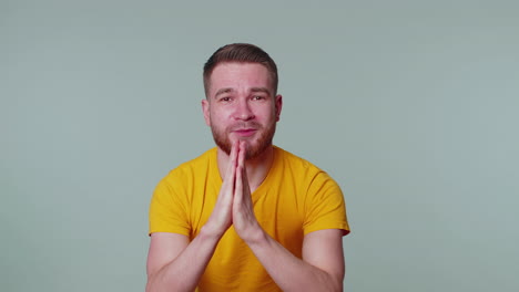 trendy young adult man praying, looking upward and making wish, asking god for help, begging apology