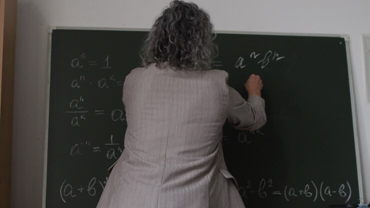 Teacher writing equations on a chalkboard