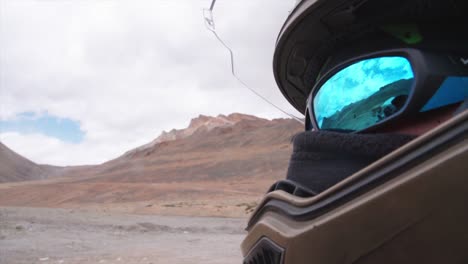 a close up of a motorbike rider's helmet and glasses with the himalayas in the background