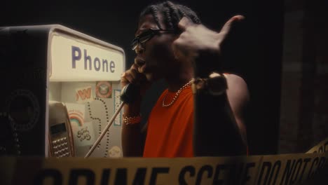 gritty black man talking on payphone at crime scene during night