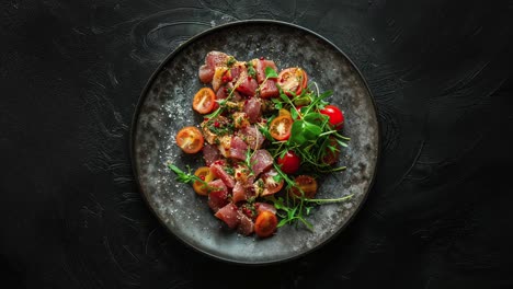 tuna salad with tomatoes and arugula on a black plate