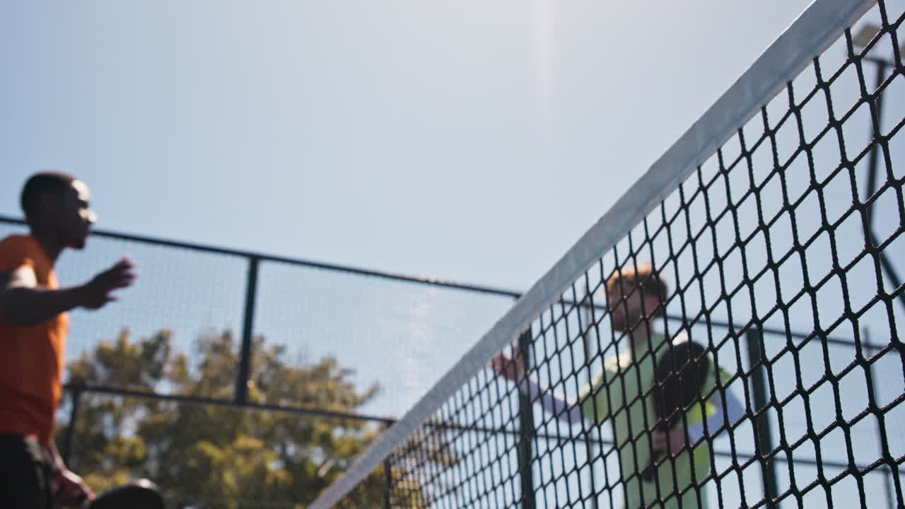 Due Uomini che si Stringono la Mano sopra la Rete da Padel in una Giornata di Sole