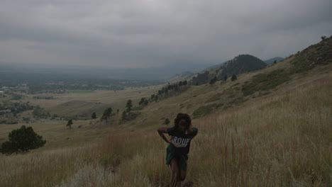 chica negra adulta caminando a través de las montañas rocosas nubladas en colorado