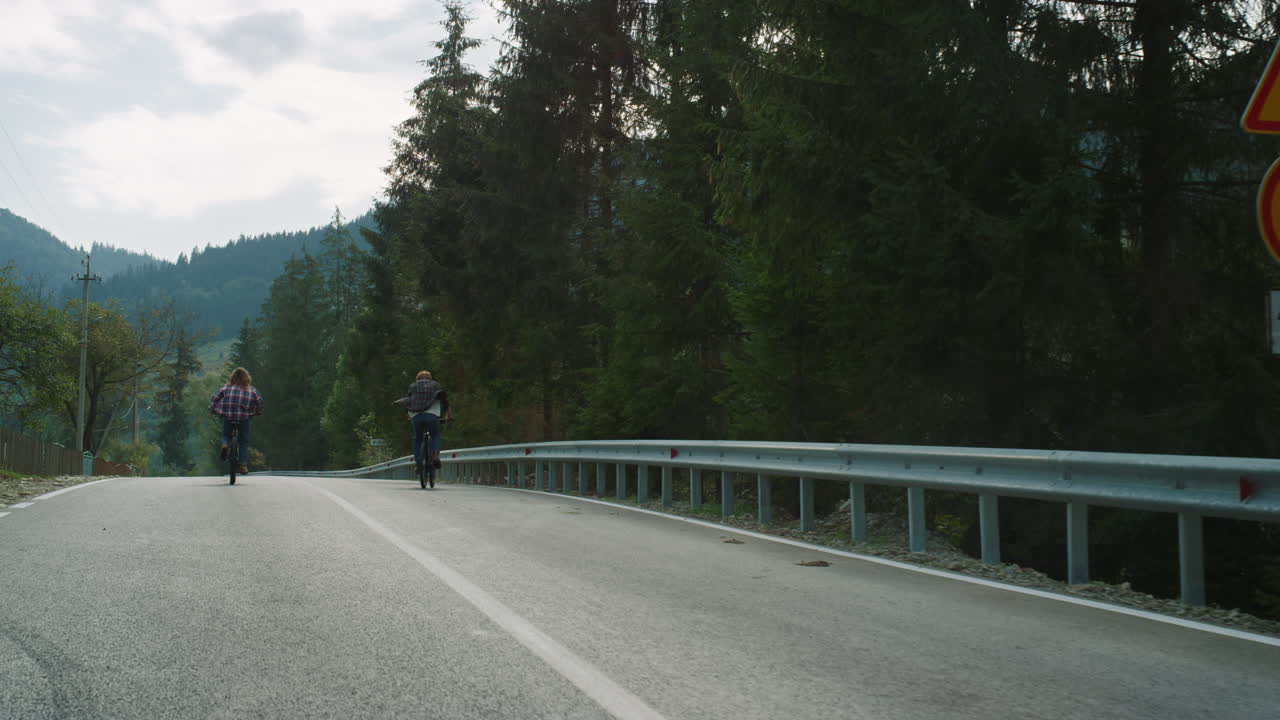 Coppia sportiva in bicicletta nella foresta su strada. Viaggiatori che pedalano in montagna.