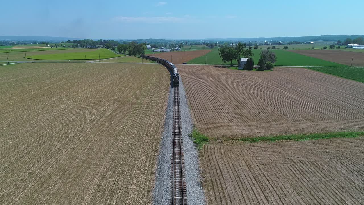 위에서 볼 수 있는 증기 여객 열차가 가까이 다가오고, 느린 움직임으로  ⁇ 은 날에 수확 된 농지를 통해 여행하고 있습니다.