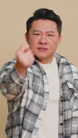 Angry aggressive asian man showing fig negative gesture refusal fig sign rapacious avaricious