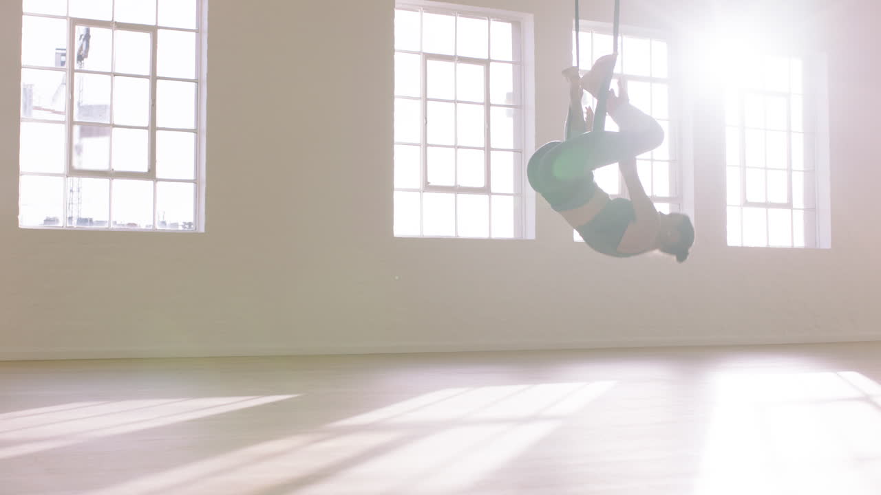 una mujer practicando yoga aéreo colgando boca abajo usando una hamaca disfrutando de un estilo de vida saludable haciendo ejercicio en el estudio entrenando meditación al amanecer
